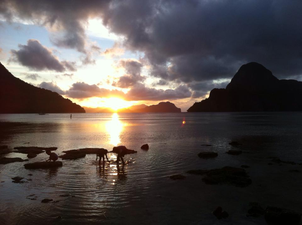 Children playing in the water at sunset in El Nido, Philippines.